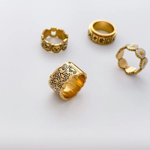 Detailed set of four gold rings featuring Keith Haring style doodles and mahjong elements