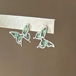 Vue rapprochée de boucles d'oreilles papillon en argent avec émail vert et motifs fleurs
