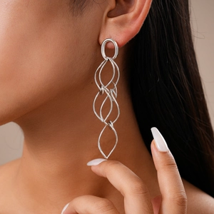 Modern silver geometric multi-layer intertwined loop earrings worn by a model