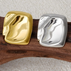 Detail of square hammered metal stud earrings in gold and silver finishes on wood