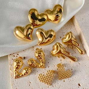Détails de quatre boucles d'oreilles cœur dorées aux textures lisses et martelées