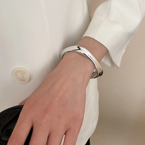 Close-up of irregular wave silver bracelet with a polished mirror finish on model wrist