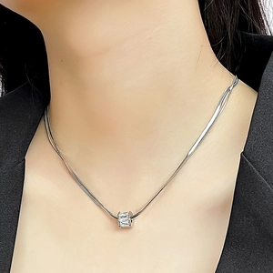 Close-up of minimalist silver snake chain necklace with a crystal geometric pendant on a model