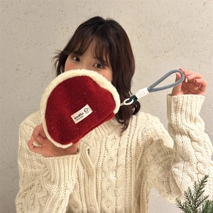 Rote Kosmetiktasche aus Filz mit Plüschbesatz, gehalten von einer Frau im Strickpullover
