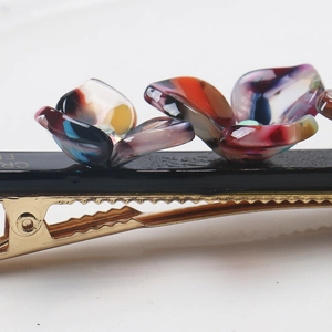 Detailed close-up of a floral acetate hair clip with iridescent resin and non-slip metal base