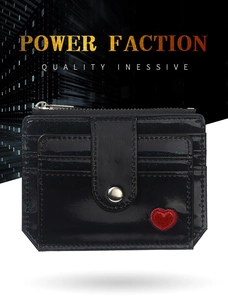 Gros plan sur un porte-cartes en cuir verni noir avec broderie coeur rouge et bouton pression