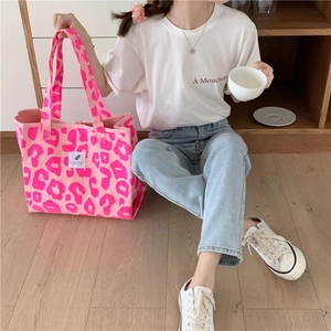 Detailed macro view of large pink leopard print canvas tote bag with woven label