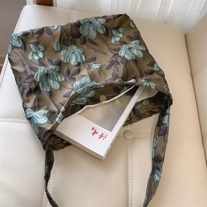 Dettaglio del tessuto jacquard floreale verde scuro di una borsa con chiusura magnetica