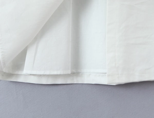 Close-up of high-quality stitching and hem detail on a white French retro cotton dress