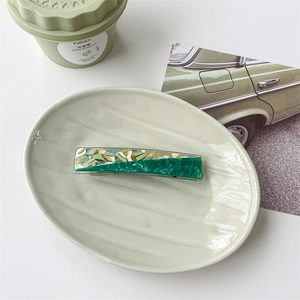 Detail of a rectangular acetate hair claw with green terrazzo pattern and gold flakes