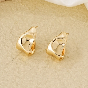Macro view of polished gold irregular lava earrings on a textured stone base