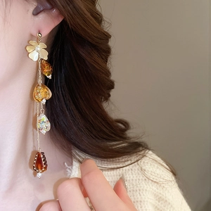 Gros plan de boucles d'oreilles à fleurs et glands ambrés portées par un mannequin