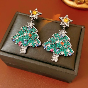 Detailed shot of Christmas tree earrings with colorful rhinestones on a jewelry box