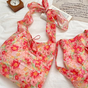 Detail of floral summer tote bag with vibrant tropical print and knotted ribbon straps