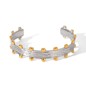 Detail view of two-tone open bangle with silver textured metal and gold spheres