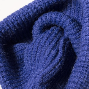 Vista macro che mostra la morbida trama di un berretto in maglia grossa blu scuro per l'inverno.