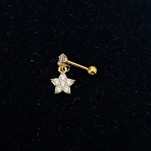 Macro shot of gold star-shaped cartilage earring with clear zircon inlay and ball back