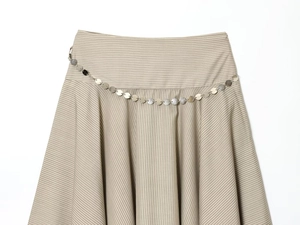 Détail d'une jupe midi rayée avec ceinture à disques métalliques et texture tissée