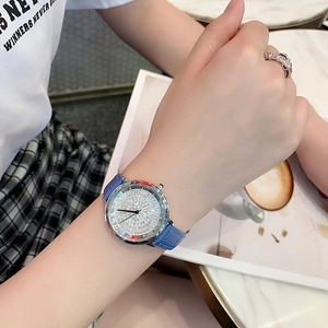 Detail view of a luxury quartz watch with full crystal bezel and blue leather strap
