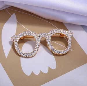 Detail of a gold eyeglasses brooch with crystal rhinestones on elegant silk fabric