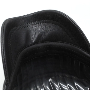 Detail of black flat top cap featuring lychee grain faux leather brim and neat stitching