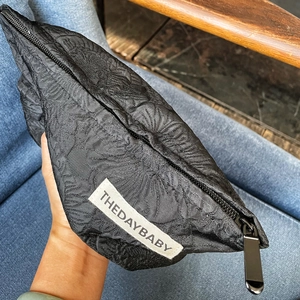 Detail view of black quilted makeup bag featuring a canvas texture and a top zipper closure