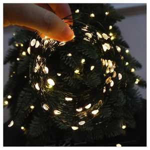 Close-up of warm yellow LED fairy lights on a dark green Christmas tree backdrop