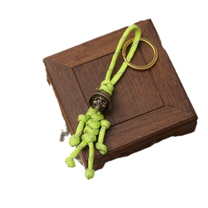 Neon green paracord skull keychain with bronze helmet bead on a rustic wooden base