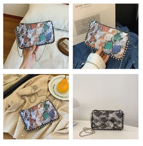 Detail of snake skin pattern envelope bag with colorful patchwork and metal chain strap