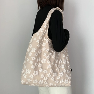 Detail of beige canvas tote bag with white 3D floral texture and spacious interior design