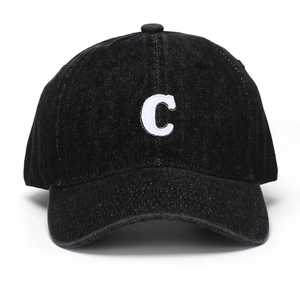 Close-up of the white embroidered letter C on a vintage black denim baseball cap