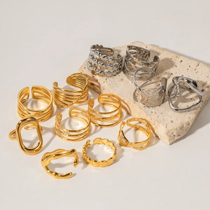 Minimalist stainless steel rings in gold and silver finishes on textured stone base
