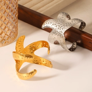 Detail of starfish open bangle with hammered texture in gold and silver finish on tray