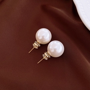 Detailed close-up of large white pearls and gold stud backs on dark brown silk background