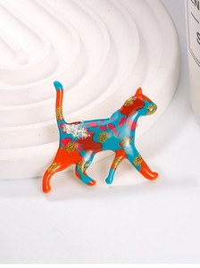 Close-up of a colorful enamel cat brooch with gold glitter and vibrant orange and blue spots