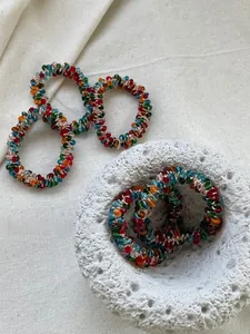 Close-up of colorful faceted crystal beaded hair ties on natural white linen texture