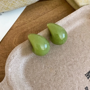 Close-up of minimalist resin drop earrings in green marble texture on wooden base