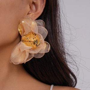 Gros plan de boucles d'oreilles fleurs en mousseline champagne sur un mannequin élégant