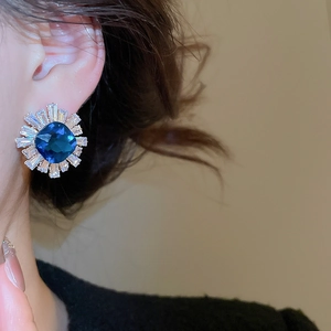 Close-up of blue sunflower earrings with rectangular zircon on model's ear