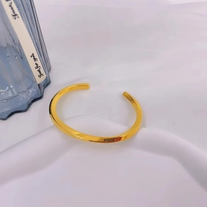 Detailed view of an adjustable gold Möbius bangle with a polished finish and open C-shape