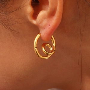 Makroaufnahme von 18K vergoldeten Spiral-Ohrringen an einem weiblichen Ohrmodell
