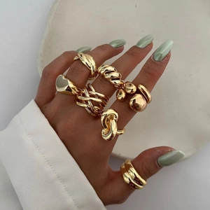 Close-up of stacked gold rings featuring heart and twisted designs on a model hand