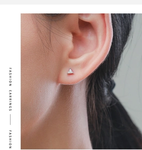 Close-up of minimalist sterling silver triangle stud earring with sparkling zircon on ear