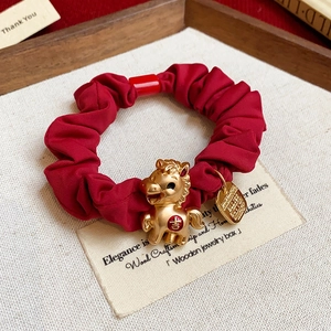Vue macro du chouchou en satin rouge avec pendentif cheval doré et symbole porte-bonheur