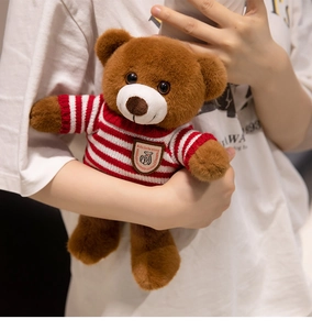 Gros plan d'un ours en peluche marron portant un pull tricoté à rayures rouges et blanches