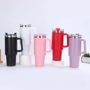 Various colors of 40oz stainless steel tumblers with handles and straws on white stands