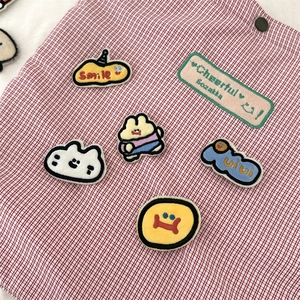Detail view of colorful cartoon embroidery patches on red and white checkered fabric