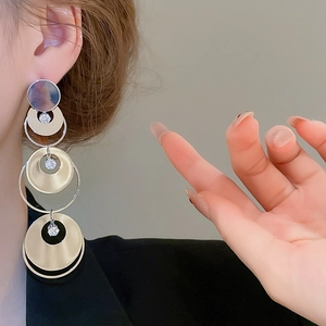 Macro shot of gold and silver geometric drop earrings with sparkling zircon accents