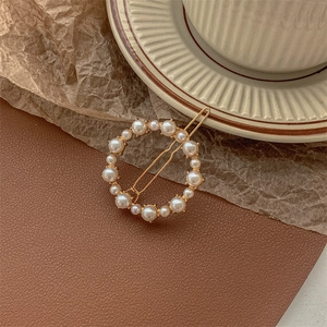 Detail shot of vintage round pearl hair clip with gold metal frame and elegant pearls