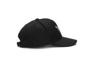 Detail of adjustable metal buckle and breathable eyelets on a black cotton baseball cap